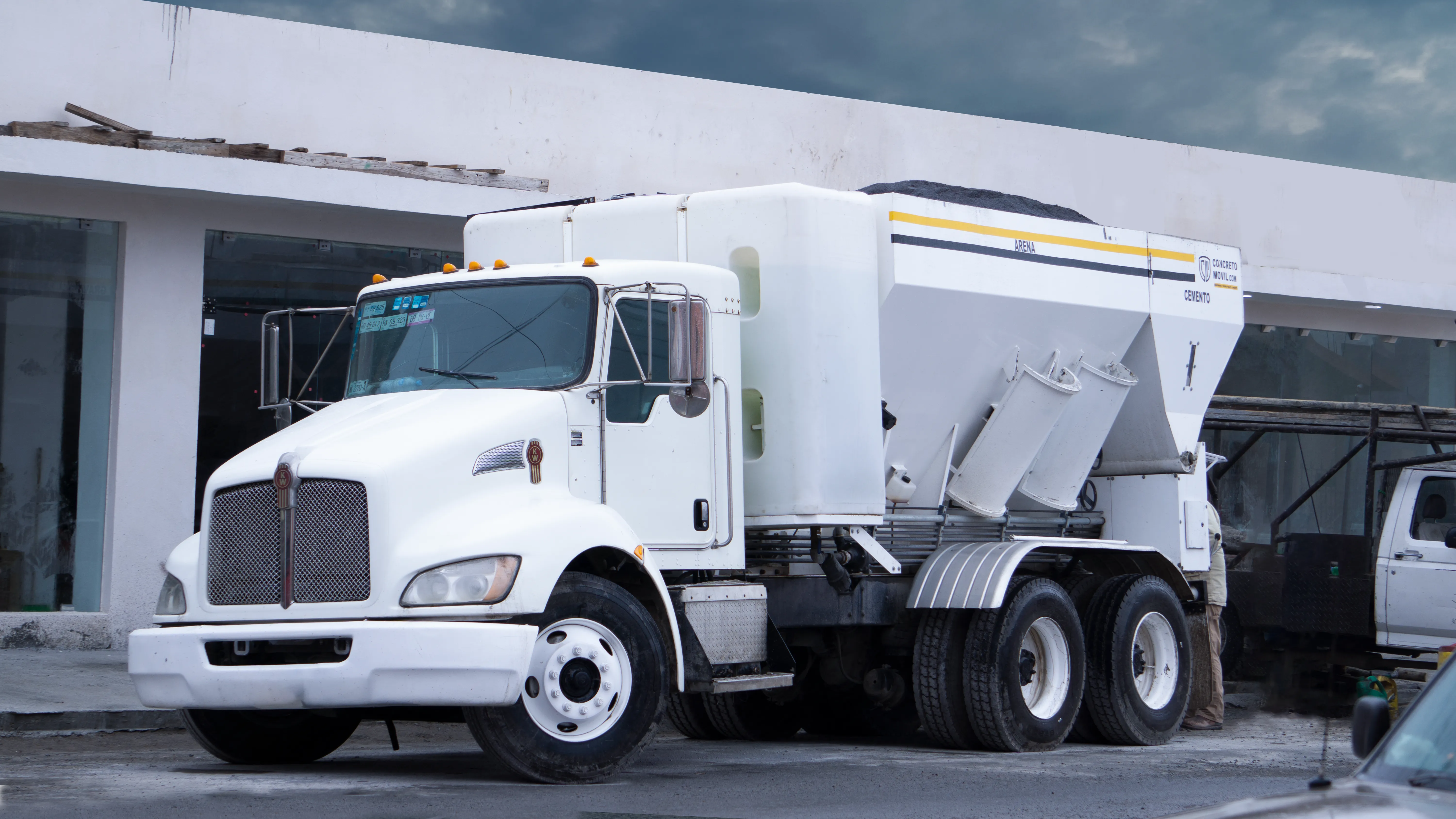 Camión Kenworth blanco en obra civil para saber ¿Cuánto cuesta rentar una planta de concreto móvil? en la ciudad.